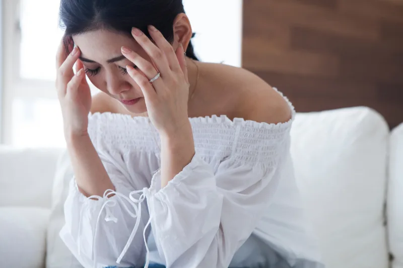 貧血で頭を抱えている女性の写真です。